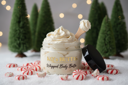 KQ’s BUTTAs Whipped Body Butta 4oz open jar surrounded by peppermint candies and Cypress trees