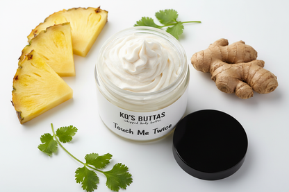 KQ's Buttas whipped body butta Touch Me Twice 4 oz open cosmetic jar surrounded by pineapple, ginger and cilantro